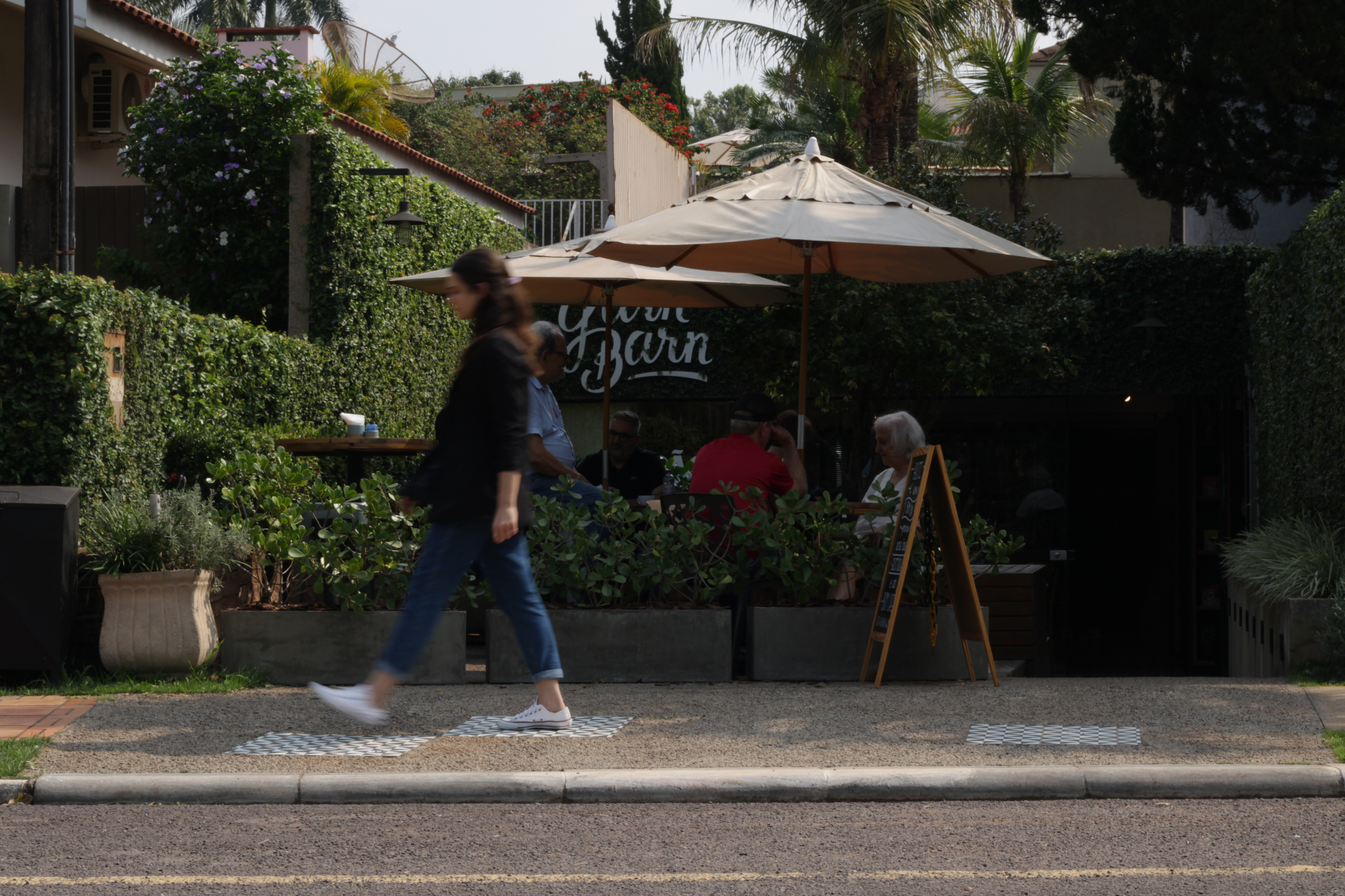 Fachada do Yarn vista da rua, com guarda-sóis creme, plantas e área externa em Toledo/PR.